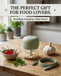 PrepEase Electric Garlic Chopper in sage green with USB-C cable, garlic and chili on a wooden kitchen counter